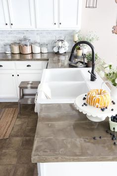 a cake sitting on top of a white plate in a kitchen next to a sink