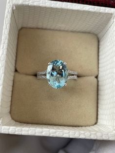 an oval cut blue topaz ring in a white box with a diamond band on it