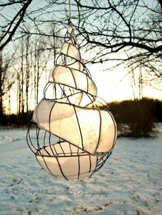 a white light hanging from a tree in the snow