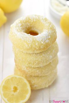 a stack of lemon donuts sitting on top of a table next to some lemons