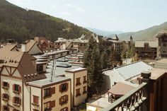 a view of some buildings and mountains in the distance with trees on either side of them