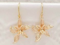 "These are pair of sophisticated and lovely orchid earrings. The beautiful shinning golden plated flower are enhanced with brushed stroke petals. They hang underneath golden plated French ear wires. The earrings measure approximately (32mm) 1.3 inches from the top of the ear wires to the bottom of the flowers. They are perfect for many occasion and everyday wear. They are also a great idea for gift giving and as a little treat for yourself. Your earrings will present in a gift box and tied with Cheap Gold Earrings With Birth Flower Detail, Dainty Gold Flower Earrings For Anniversary, Delicate Gold Flower Earrings, Gold Delicate Flower Earrings, Gold Flower Earrings With Ear Wire, Delicate Gold Flower Earrings For Formal Events, Delicate Gold Flower Earrings For Anniversary, Delicate Gold Flower Earrings For Formal Occasions, Gold Dangle Earrings With Flower Decoration