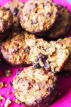 several muffins on a pink plate with crumbs all over them and one is cut in half