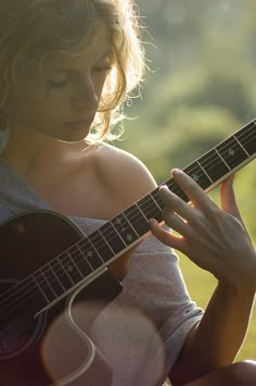 a woman is playing an acoustic guitar outside