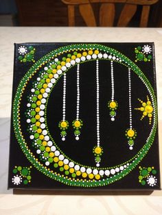 a painting with beads and flowers on it sitting on a table next to a chair