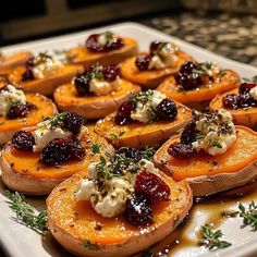 baked sweet potatoes with cranberries and cheese on a white platter, ready to be served