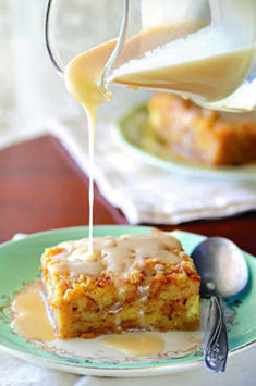 a piece of cake on a plate being drizzled with icing from a pitcher