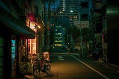 a bike parked on the side of a street next to a tall building at night