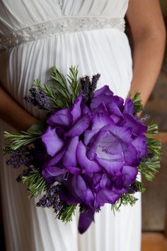 a woman in a white dress holding a purple bouquet