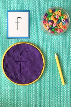 a table topped with a purple cake next to a bowl of beads and a pen