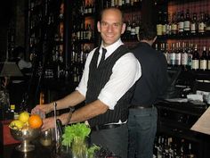 a man standing in front of a bar cutting an orange