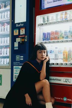 a woman sitting in front of a vending machine