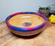 a wooden bowl sitting on top of a table next to a potted yellow plant