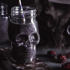 a glass jar filled with liquid next to some berries