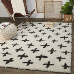 a white rug with black crosses on it in front of a chair and potted plant