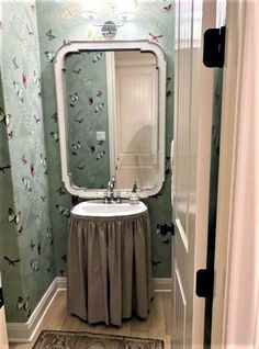 a bathroom with green wallpaper and a white sink in front of a large mirror