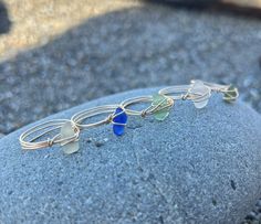 three rings with sea glass on them sitting on top of a rock