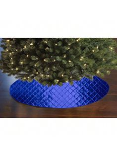 a christmas tree in a blue vase with lights on it's branches and the base