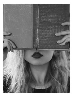 black and white photograph of a woman hiding her face behind a book