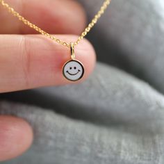 Beautiful and lovely super tiny black happy face charm necklace.  Made of white enamel gold smiley face charm with skinny gold plated brass chain. Soft and warm. Great for gift , everyday or special occasions. Your item will ship in a gift box. Please feel free to contact me if you have any questions. ♥ Length 14" -20" chain ♥ Charm 1/4"  ♥ Gold plated over brass / white enamel ♥ Delivery Time Fast shipping within 1 - 3 days  ♥  See more Rudiana Accessories  Rudiana.etsy.com Smiley Face Necklace, Face Necklace, Necklace White, Gold Enamel, Happy Face, Brass Chain, Smile Face, White Enamel, Smiley Face