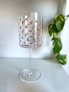 a wine glass sitting on top of a table next to a green leafy plant