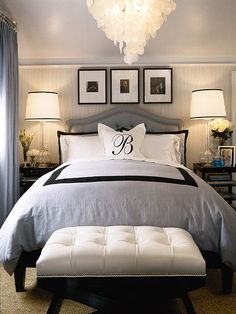 a bedroom with white and black bedding, pictures on the wall, and chandelier