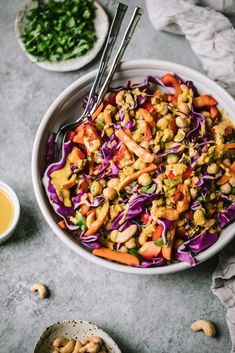 a white bowl filled with cabbage, carrots and chickpeas next to a spoon