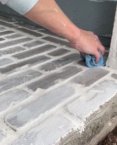 a person with a sponge on top of a cement block wall that is being worked on