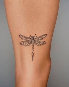 a woman's thigh with a dragonfly tattoo on it