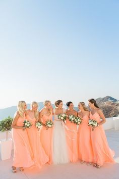 a group of women standing next to each other on top of a white roof holding bouquets