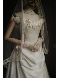 a mannequin wearing a wedding dress and veil with flowers on the bustle