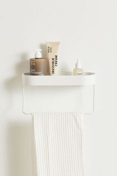 a white towel hanging on the wall next to a shelf with bottles and lotion