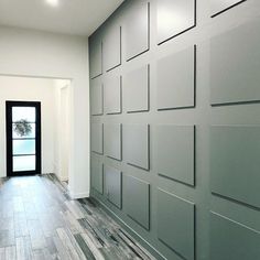 an empty room with wood flooring and gray wall covering it's walls is shown