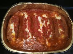 a metal pan filled with meat covered in marinara sauce on top of a stove