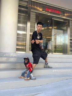 a young man standing next to a little boy on the steps in front of a building