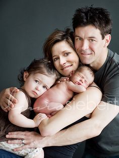 a man and woman holding two babys in their arms