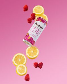 a can of humma zero surrounded by lemons and raspberries on a pink background