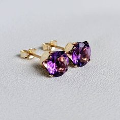 Striking deep shades of purple when seen from different angles. These earrings are available in your choice of a 14K gold-filled setting, 14k solid gold setting, or .925 solid silver setting. Both gold metals are tarnish resistant, water resistant, and hypoallergenic. These timeless stones are 6mm, making is roughly a half carat each. Whether you need a pair of earrings for everyday use or a special occasion, these classic studs won't disappoint. IMPORTANT: Both 14k solid gold and 14k gold-fille Purple Earrings Studs, Amethyst Studs, Gold Bond, Purple Earrings, Gemstone Stud Earrings, Gemstone Studs, Amethyst Earrings, Gold Filled Jewelry, Amethyst Gemstone