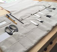 scissors and other tools are laid out on a piece of fabric, along with some paper