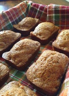 freshly baked muffins sitting in a basket on top of a table with a checkered cloth