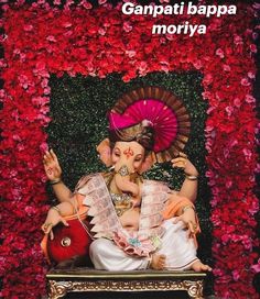 an image of ganpatia in front of red and pink flowered wall with the words ganpai bappa mohriya written on it