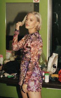 a woman is standing in front of a mirror brushing her hair and looking at the camera