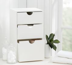 two white boxes sitting on top of a table next to a plant and towel dispenser