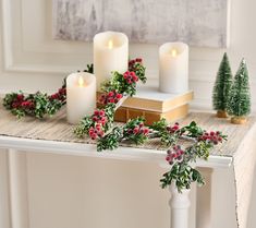 candles and greenery sit on a table in front of a christmas card board with evergreens