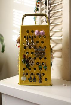 a gold purse with lots of earrings hanging from it's sides on a white shelf