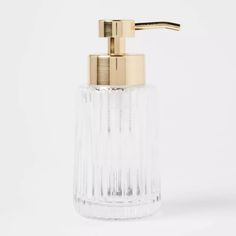 a clear glass soap dispenser with a gold faucet