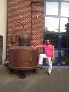 a man standing next to a large wooden barrel in front of a red brick building