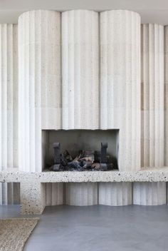 an empty room with a fireplace in the center and white columns on the wall behind it