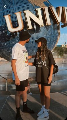 two people standing next to each other in front of a large sign that says universal