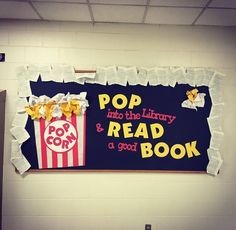 a sign that says pop into the library and read a good book with popcorn on it